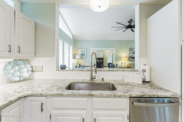 kitchen with stainless steel dishwasher, tasteful backsplash, a ceiling fan, white cabinets, and a sink