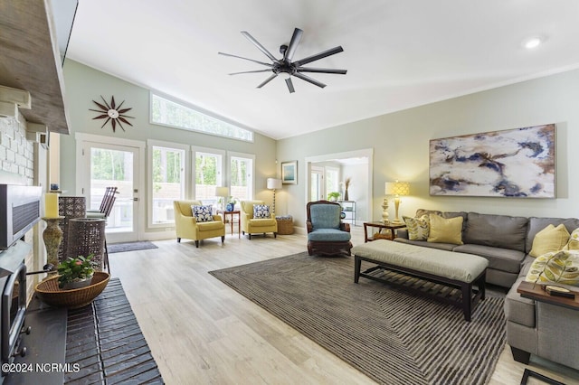 living area featuring a fireplace, lofted ceiling, ceiling fan, and wood finished floors