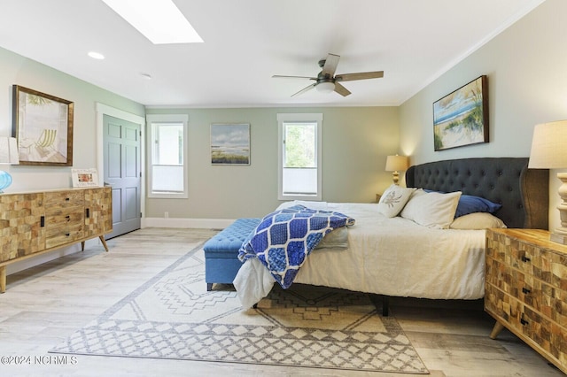 bedroom featuring light wood-style floors, baseboards, ornamental molding, and a skylight