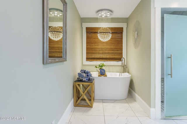 bathroom with baseboards, a freestanding bath, marble finish floor, and a notable chandelier