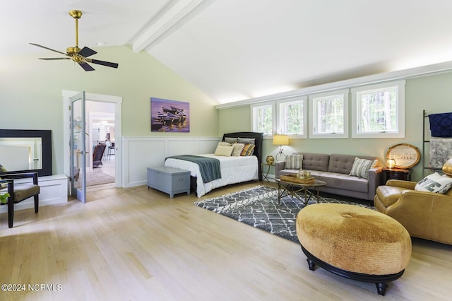 bedroom featuring light wood-style floors, ceiling fan, a wainscoted wall, and lofted ceiling with beams