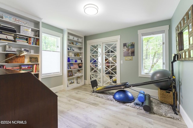 workout area with a wealth of natural light, baseboards, and wood finished floors