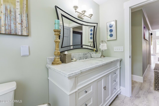 bathroom with toilet, vanity, and baseboards