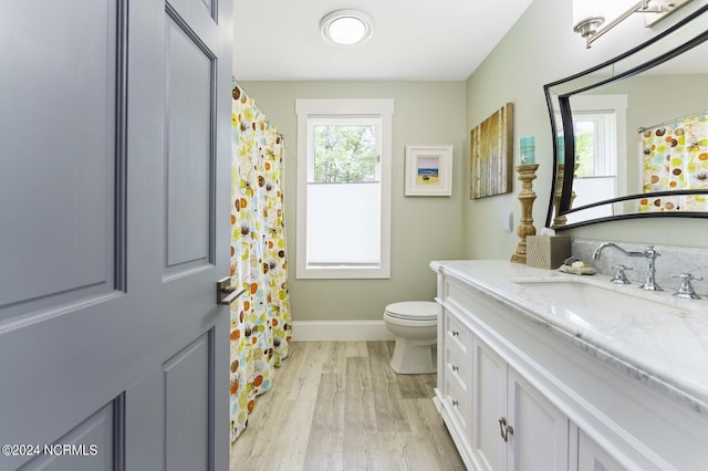 bathroom featuring toilet, vanity, wood finished floors, and baseboards