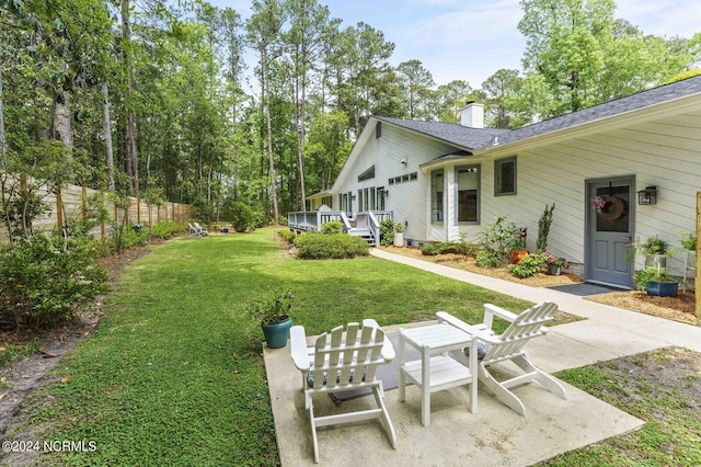 view of yard featuring a patio, a wooden deck, and fence