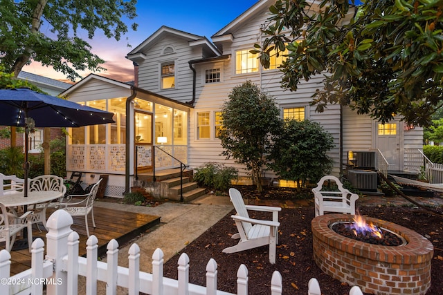 back house at dusk featuring an outdoor fire pit and central air condition unit