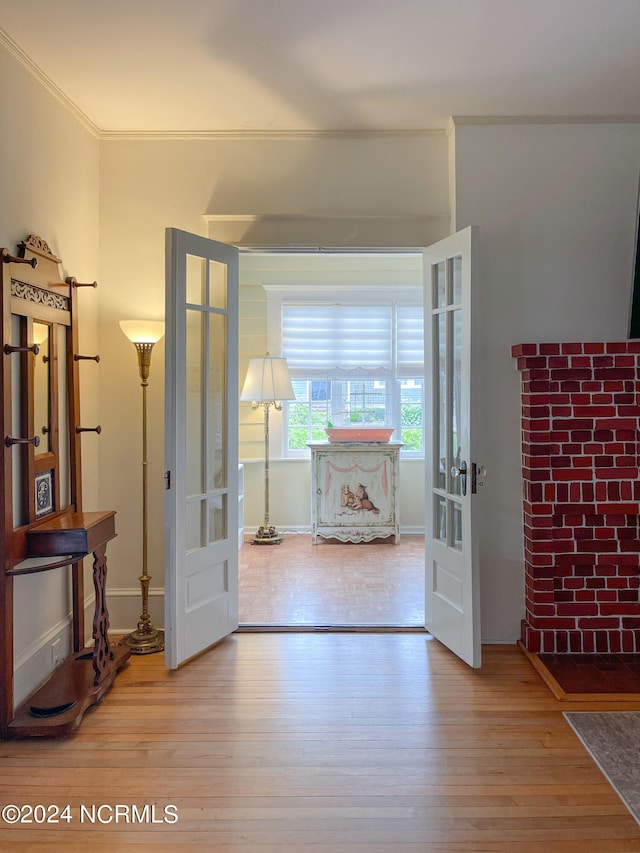 entryway with ornamental molding, hardwood / wood-style flooring, and french doors