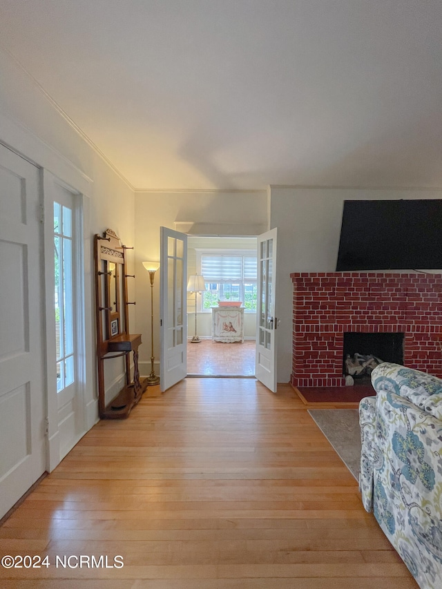 entrance foyer with crown molding, french doors, a fireplace, and light hardwood / wood-style flooring