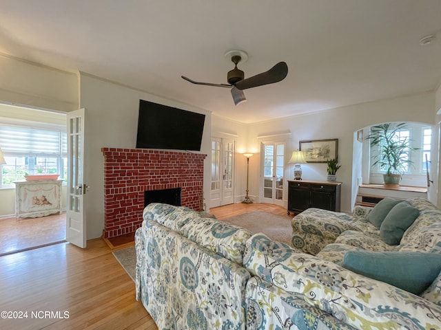 living room featuring a fireplace, ceiling fan, and light hardwood / wood-style flooring