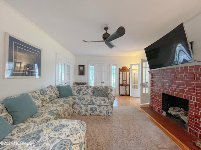 living room featuring ceiling fan, ornamental molding, hardwood / wood-style flooring, and a fireplace