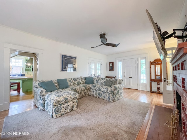 living room featuring a healthy amount of sunlight, a fireplace, wood-type flooring, and ceiling fan