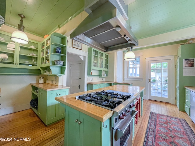 kitchen with green cabinetry, island range hood, butcher block counters, stainless steel stove, and hanging light fixtures