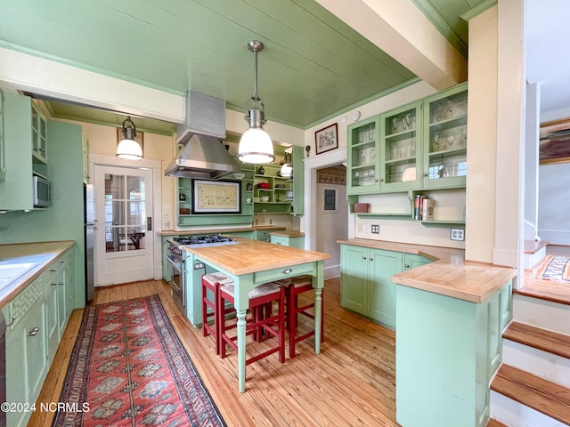 kitchen with appliances with stainless steel finishes, decorative light fixtures, wood counters, and green cabinets