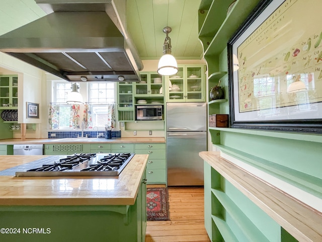 kitchen featuring light hardwood / wood-style floors, green cabinets, appliances with stainless steel finishes, island exhaust hood, and pendant lighting