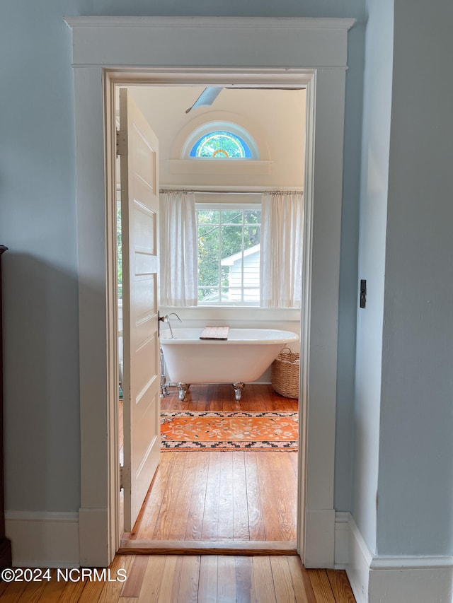 bathroom with a bath to relax in and hardwood / wood-style flooring