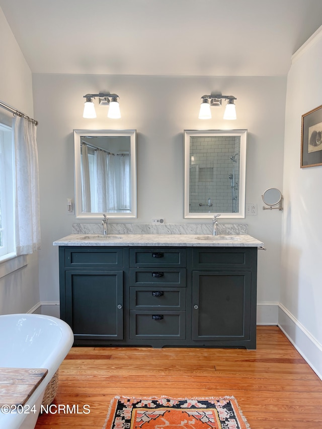 bathroom with hardwood / wood-style floors, double sink, a bathtub, and large vanity