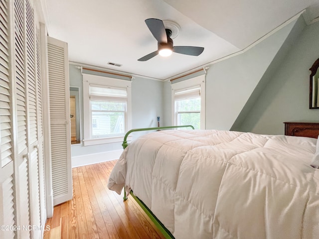 bedroom with a closet, ceiling fan, light wood-type flooring, and multiple windows