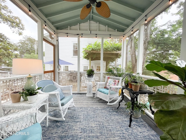 sunroom with ceiling fan, lofted ceiling with beams, and a healthy amount of sunlight