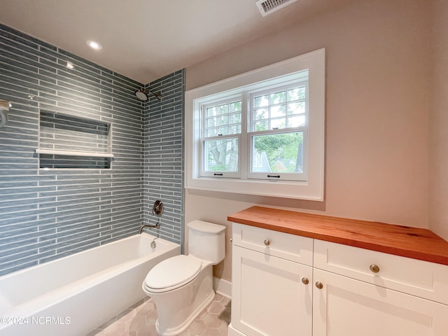 full bathroom featuring tile flooring, vanity, toilet, and tiled shower / bath combo