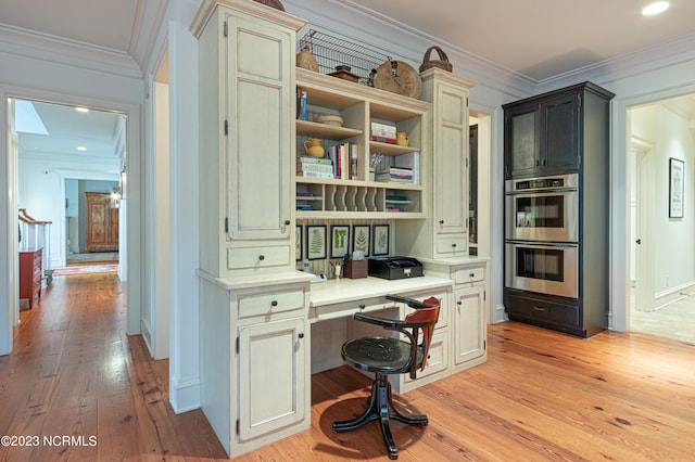 office with built in desk, ornamental molding, and light hardwood / wood-style floors