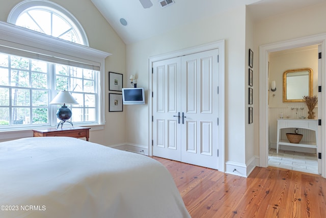 bedroom featuring ceiling fan, a closet, hardwood / wood-style floors, ensuite bath, and lofted ceiling