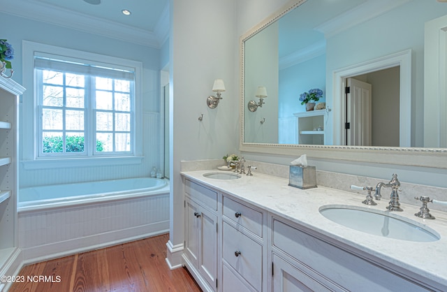 bathroom featuring double vanity, tiled tub, ornamental molding, and hardwood / wood-style flooring