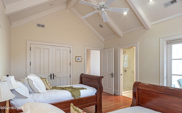 bedroom with hardwood / wood-style flooring, connected bathroom, beam ceiling, high vaulted ceiling, and ceiling fan