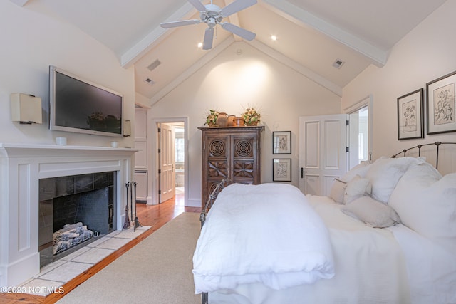 bedroom featuring light hardwood / wood-style flooring, a fireplace, ceiling fan, beam ceiling, and high vaulted ceiling