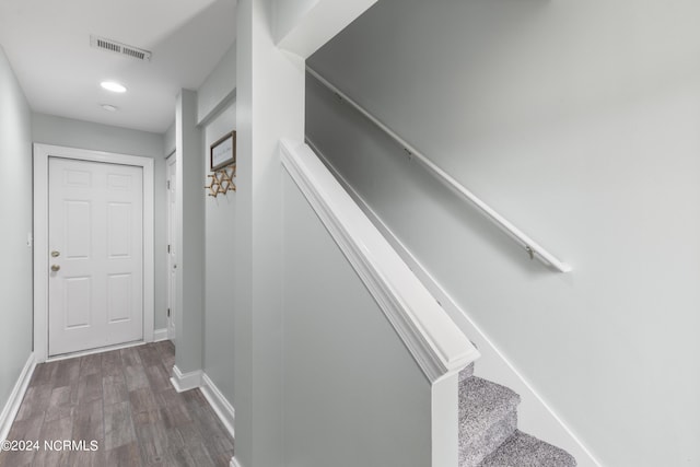 staircase with baseboards, visible vents, and wood finished floors