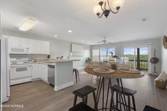 kitchen featuring a peninsula, white appliances, visible vents, and wood finished floors