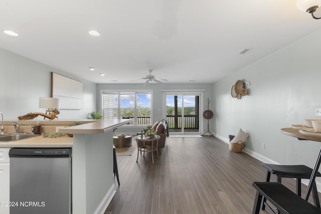 kitchen featuring dark wood-style flooring, light countertops, stainless steel dishwasher, a sink, and baseboards