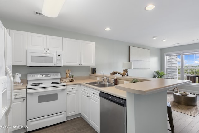 kitchen with white appliances, dark wood-style floors, a peninsula, white cabinetry, and a sink