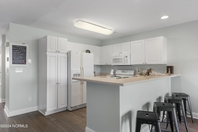 kitchen featuring white appliances, a breakfast bar, dark wood-style flooring, light countertops, and white cabinetry