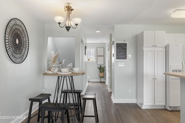 dining area featuring dark wood-style floors, baseboards, and a chandelier