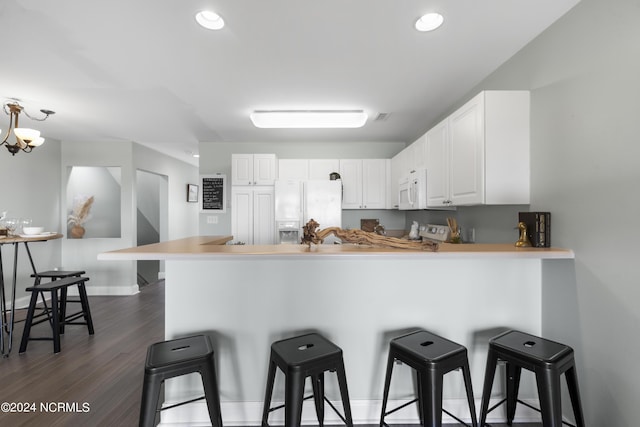 kitchen with a peninsula, white appliances, and a breakfast bar area