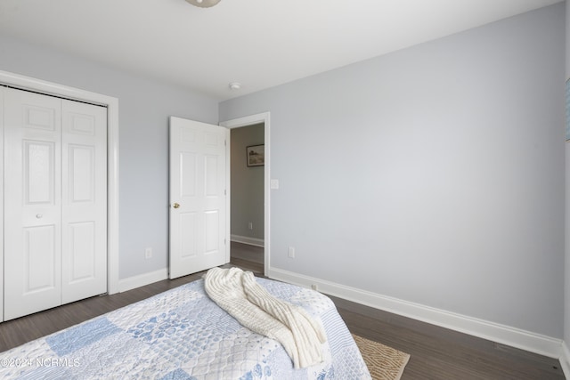 bedroom featuring dark wood-style floors, baseboards, and a closet