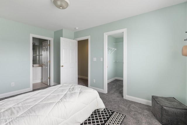 bedroom with baseboards, ensuite bath, a walk in closet, carpet floors, and a closet