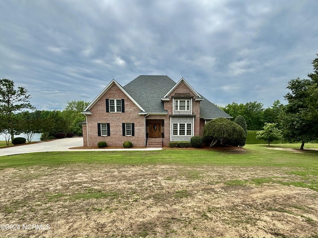 view of front of house with brick siding, a front lawn, and roof with shingles