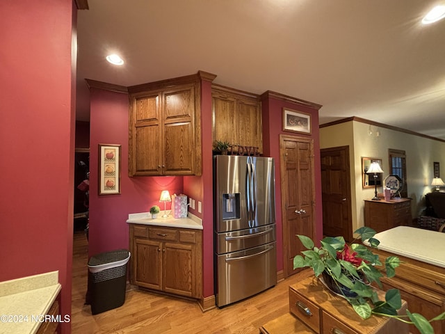 kitchen with stainless steel fridge, crown molding, and light wood-type flooring