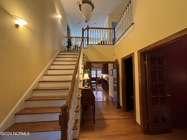 staircase with wood-type flooring and a high ceiling