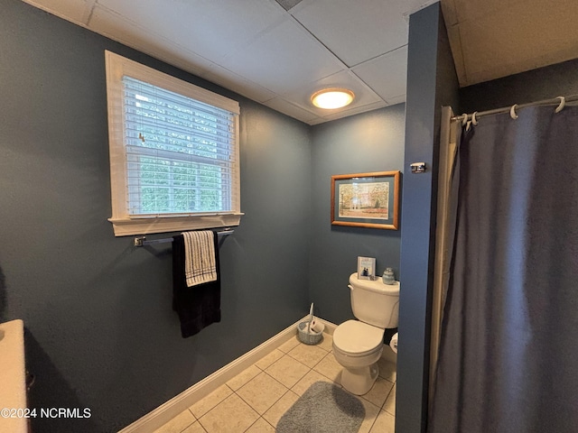 bathroom with a paneled ceiling, tile patterned flooring, toilet, and baseboards