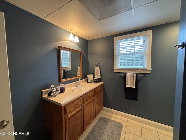 bathroom with a paneled ceiling, tile patterned flooring, baseboards, and vanity