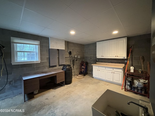 basement with concrete block wall, electric panel, and a workshop area