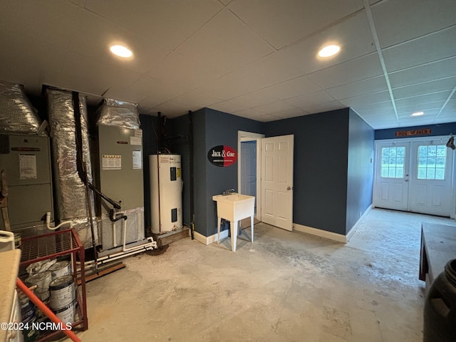 basement featuring electric water heater, a drop ceiling, and french doors