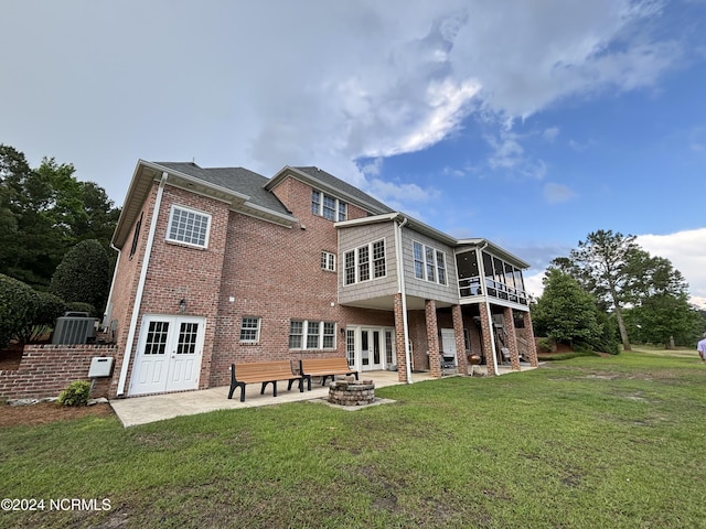 back of property with a patio area, a yard, a fire pit, and brick siding