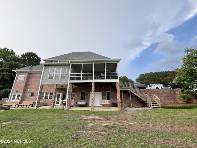 back of property featuring brick siding, a sunroom, a yard, stairway, and a patio area