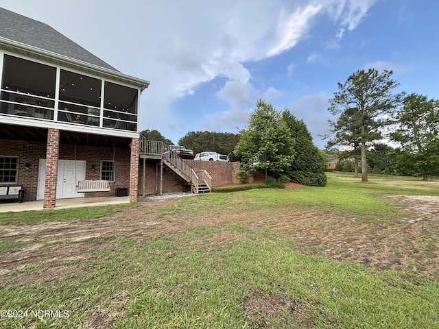 view of yard featuring a sunroom, a patio area, and stairs