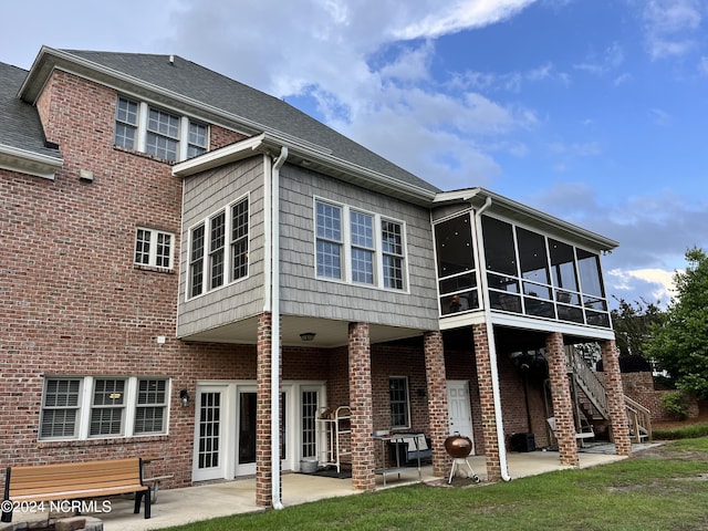 rear view of house with a lawn, a patio, a sunroom, stairway, and brick siding