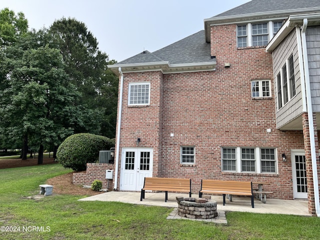 rear view of property featuring an outdoor fire pit, a patio, roof with shingles, a yard, and brick siding