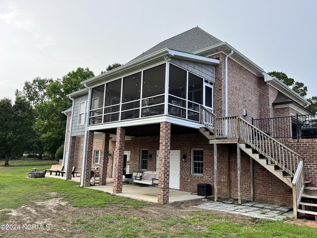 back of property with brick siding, stairway, an outdoor fire pit, a sunroom, and a patio area